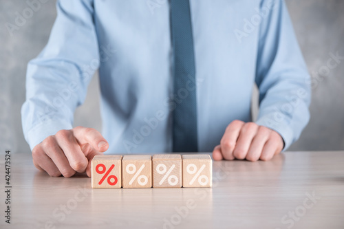 Businessman hand takes a wooden cube block depicting,shown the percentage symbol icon. Interest rate financial and mortgage rates concept.