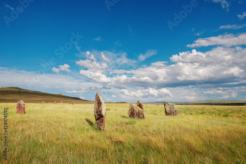 Menhirs remains of an ancient burial mound in the steppe of Khakassia against the background of mountains in the Tarpig region photo