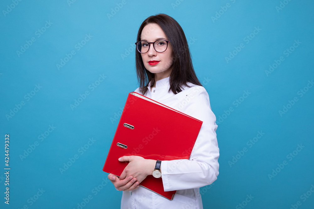 Fototapeta premium Portrait of a female doctor with a red folder on a blue background