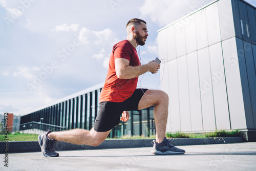 Sportsman with earphones doing lunge exercise