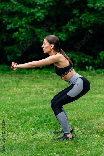 young girl goes in for sports, does squats in nature