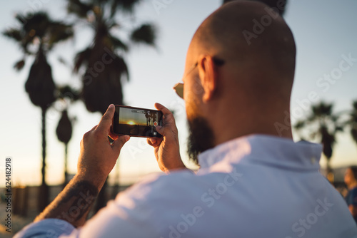 Man taking photo of sundown on street