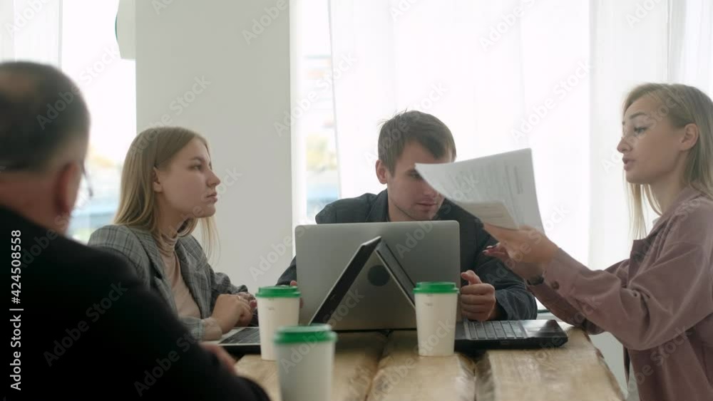 Team of creative business young employees of the company women men sit at the office desk and work on laptops discussing amendments to documents. Colleagues discuss plans for business and startups Team of creative business young employees of the company women men sit at the office desk and work on laptops discussing amendments to documents. Colleagues discuss plans for business and startups