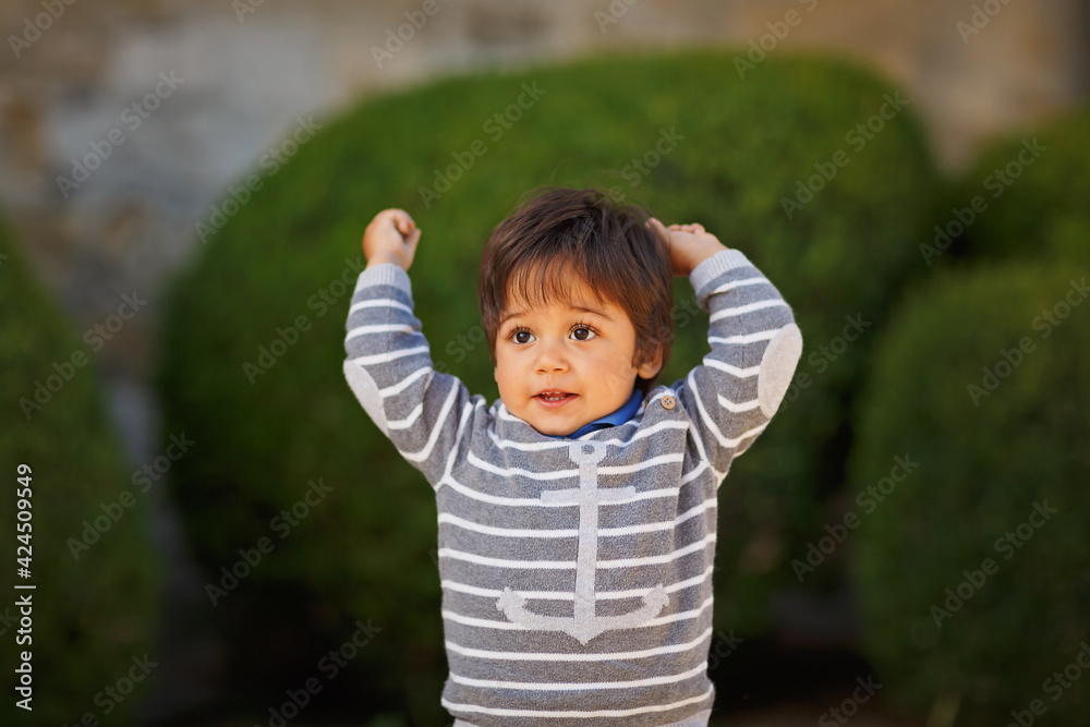 Little eastern handsome baby boy playing with pebbles outdoor in the park Little eastern handsome baby boy playing with pebbles outdoor in the park