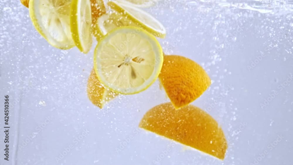 sliced juicy lemons and oranges falling into fresh water