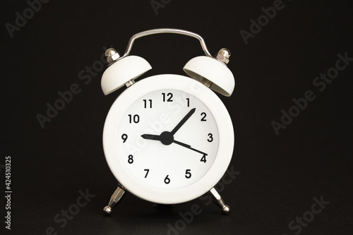 white alarm clock with hands on black background