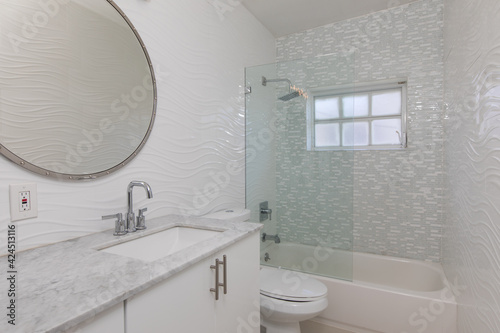 White bathroom with gray marble countertop and round mirror 