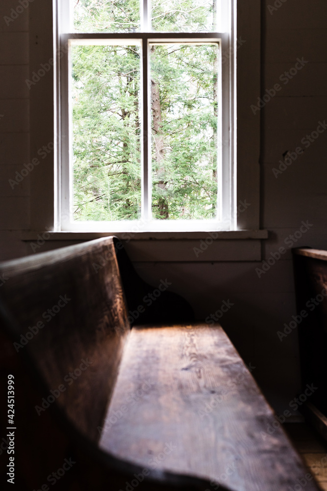 Fototapeta premium sunlight spilling through a church window, lighting the pew