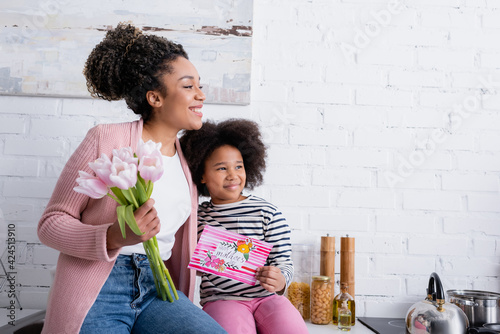 Картината върху платно Happy African American woman and girl with happy mothers day card smiling and lo