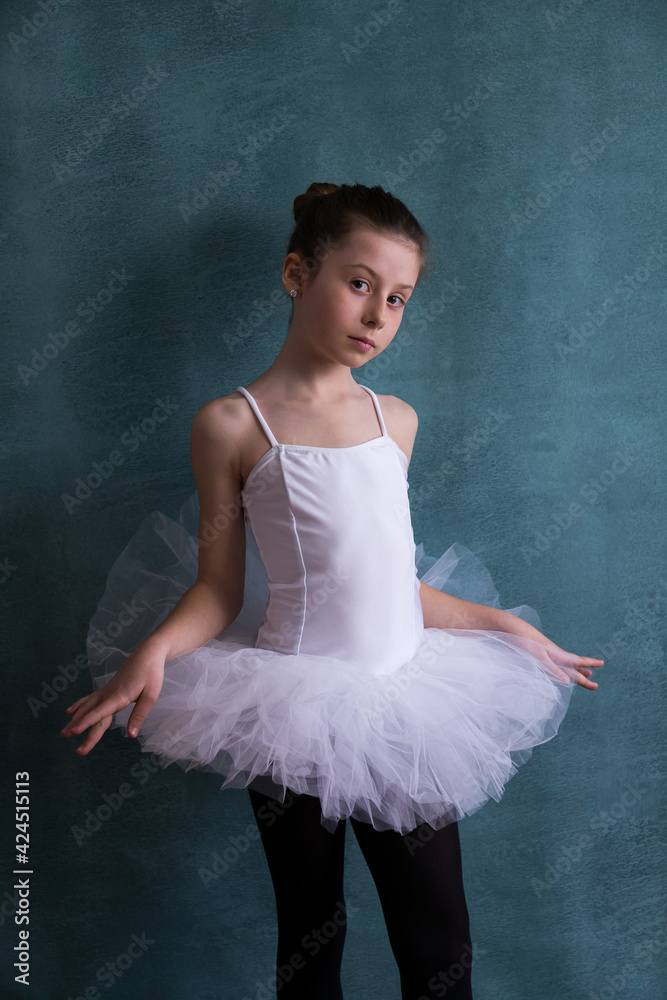 Vertical studio shot of cute graceful little girl posing with serious expression in her white ballet tutu Vertical studio shot of cute graceful little girl posing with serious expression in her white ballet tutu