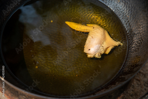 chicken frying in high temperature black pan with oil bubble