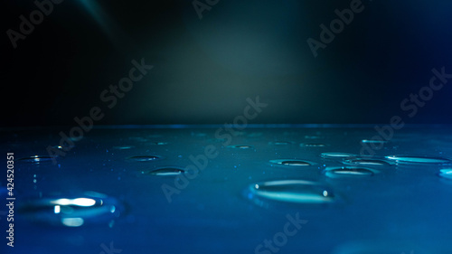 Condensation water drops on black glass background. Rain droplets with light reflection on dark window surface, abstract wet texture, scattered pure aqua blobs pattern
