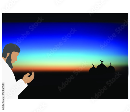 Man is praying at dawn before sunrise. The mosques are visible from afar. Ramadan Kareem concept. 