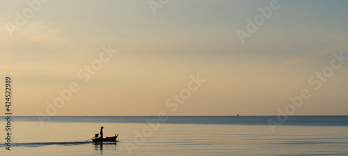 Silhouette fisherman sailing out to open sea in early morning. Very peaceful atmosphere and quiet sea with no wave at all.