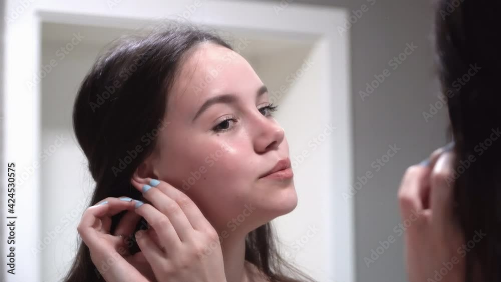 Woman putting on earrings. Dressing jewelry for a party Woman putting on earrings. Dressing jewelry for a party