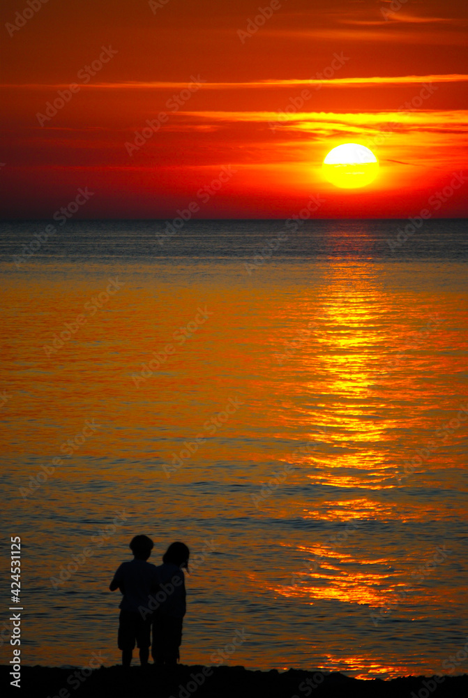 Children on the seashore by the setting golden sun Children on the seashore by the setting golden sun