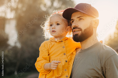 Stylish bearded father holding his little curly daughter