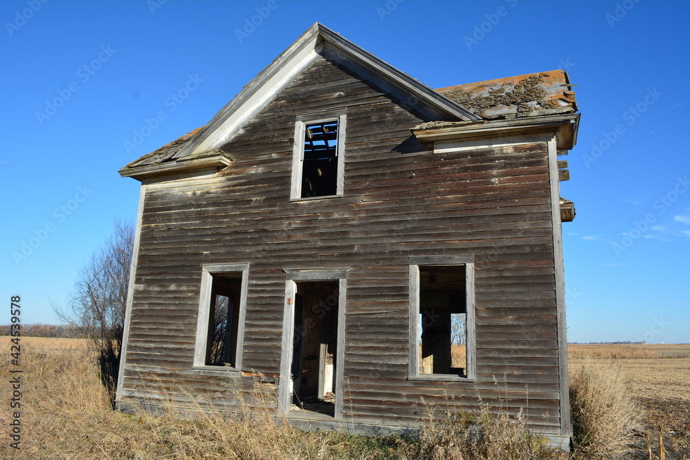 Old abandoned house with rusted roof and broken windows in winter field Old abandoned house with rusted roof and broken windows in winter field