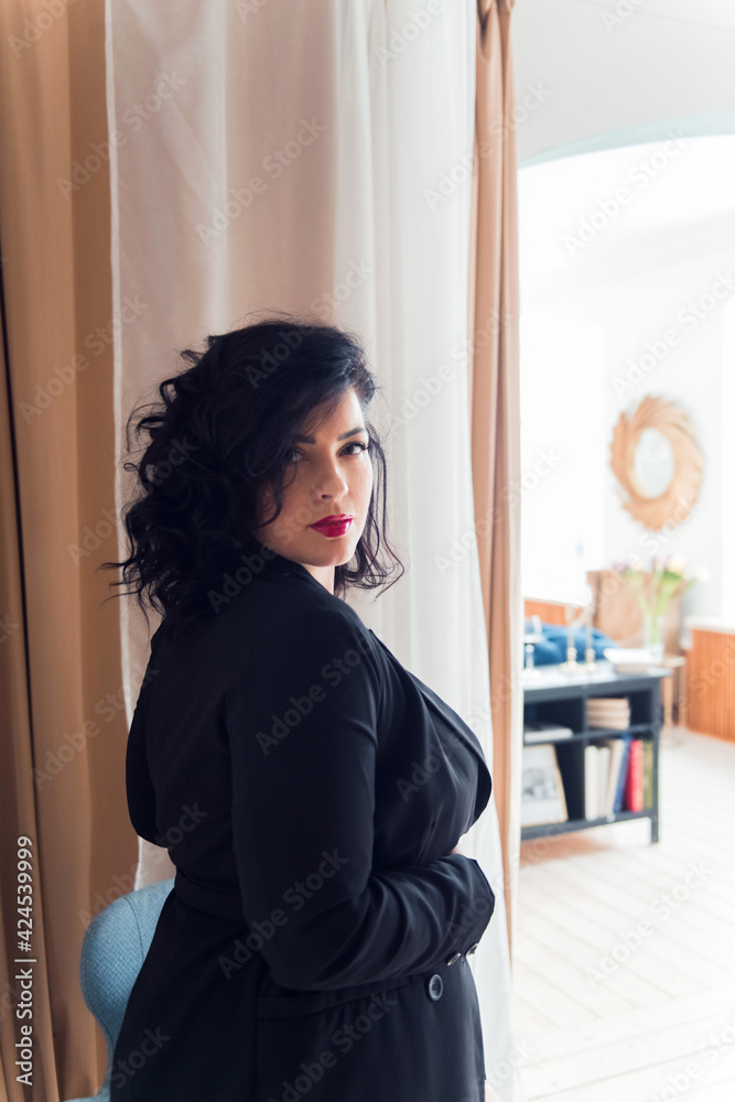 Beautiful plus size woman posing at camera, confident woman, wearing black suit