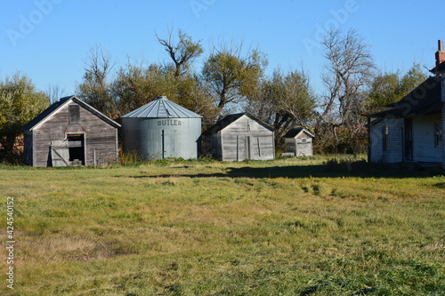 Grain bin storage next to old abandoned farm house