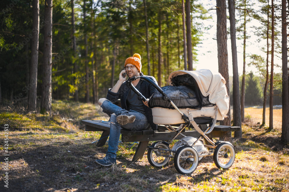 portrait of attractive nerd with glasses in the forest walks with a baby. Happy fatherhood with the wagon portrait of attractive nerd with glasses in the forest walks with a baby. Happy fatherhood with the wagon
