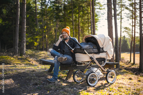 portrait of attractive nerd with glasses in the forest walks with a baby. Happy fatherhood with the wagon