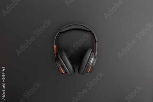 Headphones on black leather background. Music concept. Flat lay composition. Top view.