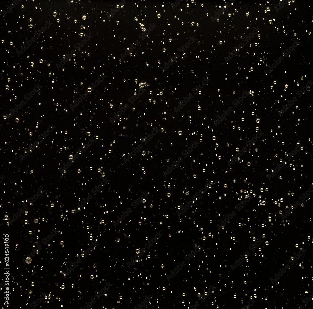 Solid dark glass filled with air bubbles and light as background Solid dark glass filled with air bubbles and light as background