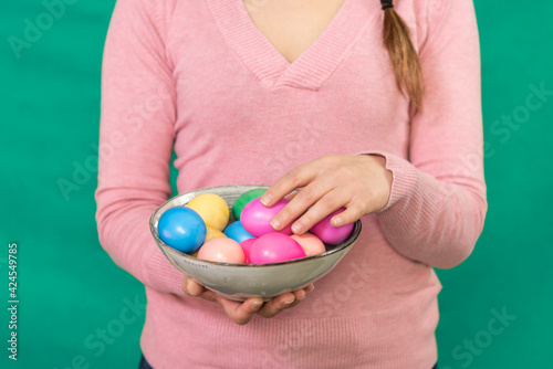 Happy young woman holding a plate with Easter eggs.