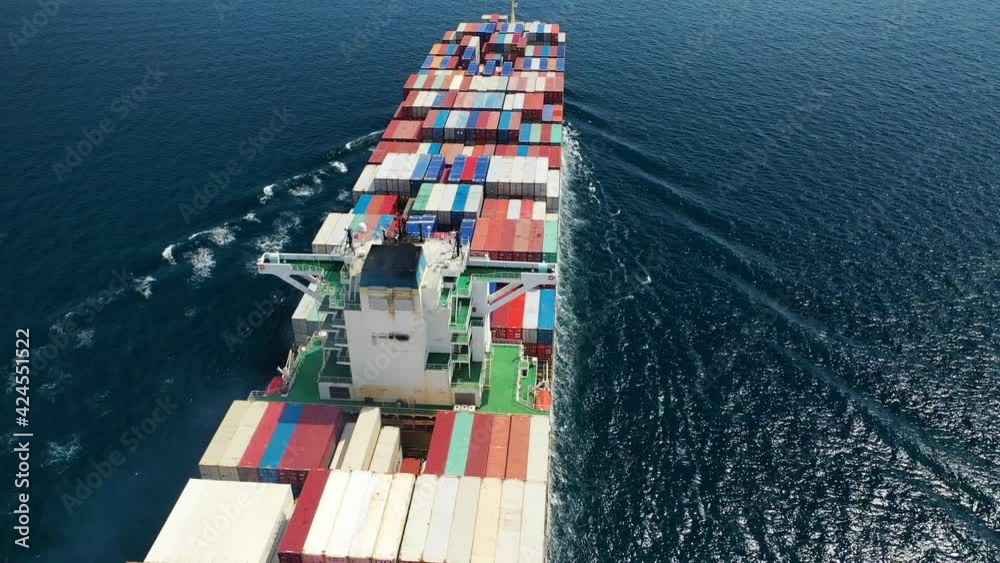 Aerial drone top view video of fully loaded container ship cruising open ocean sea for logistics import export, shipping or transportation