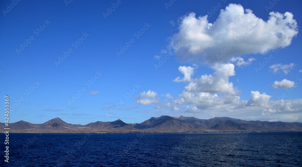 Coast of Jandia seen from the sea with intense blue sky and some clouds, Fuerteventura, Canary Islands, Spain 