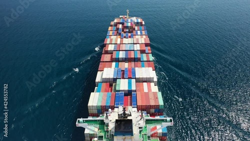 Aerial drone flight above fully loaded container ship cruising open ocean sea for logistics import export, shipping or transportation