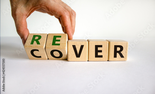 Recover symbol. Concept word 'recover' on wooden cubes on a beautiful white table. Businessman hand. White background. Business and recover concept. Copy space.