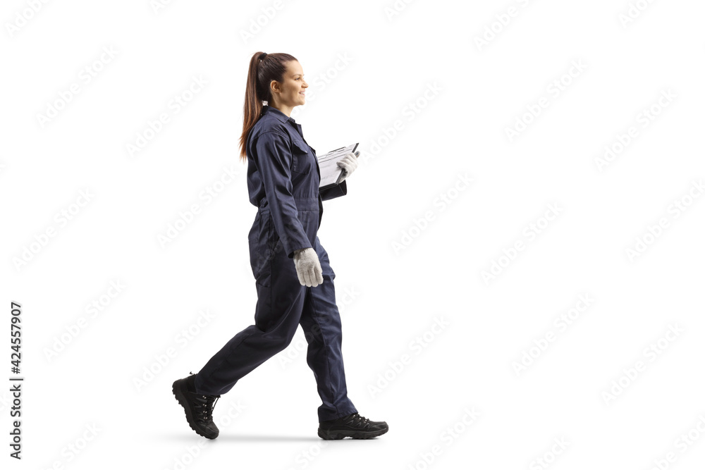 Full length portrait of a female worker in a uniform walking and holding a clipboard Full length portrait of a female worker in a uniform walking and holding a clipboard