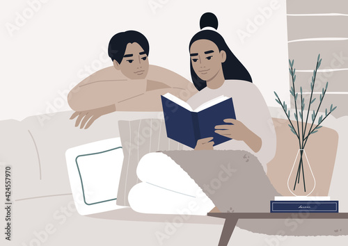 Weekend leisure activities, an Asian couple reading a book together in the living room, cozy domestic life during the lockdown