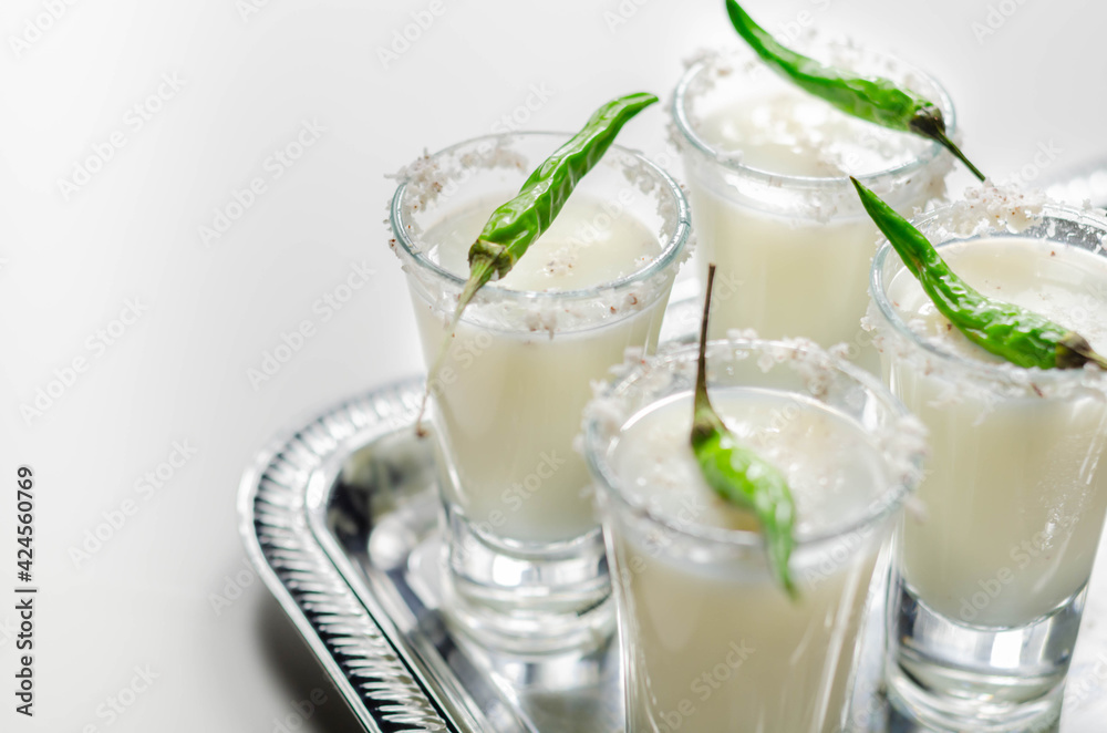 Coconut cocktail in drink shot glass decorated with coconut flakes and green bird eye chilli served on a silver tray Coconut cocktail in drink shot glass decorated with coconut flakes and green bird eye chilli served on a silver tray