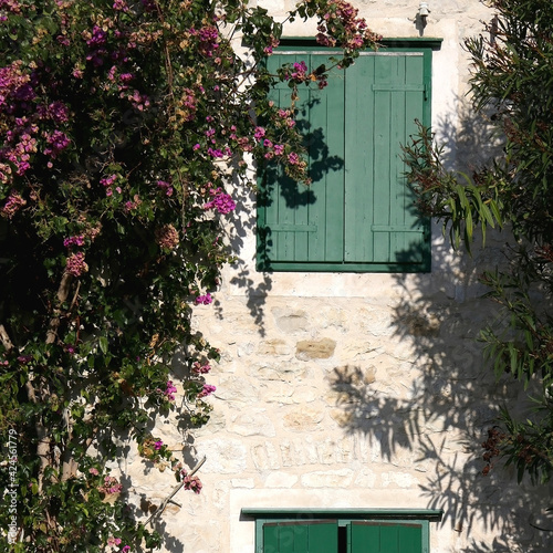 Traditional Mediterranean house with wooden window shutters and flowers.
