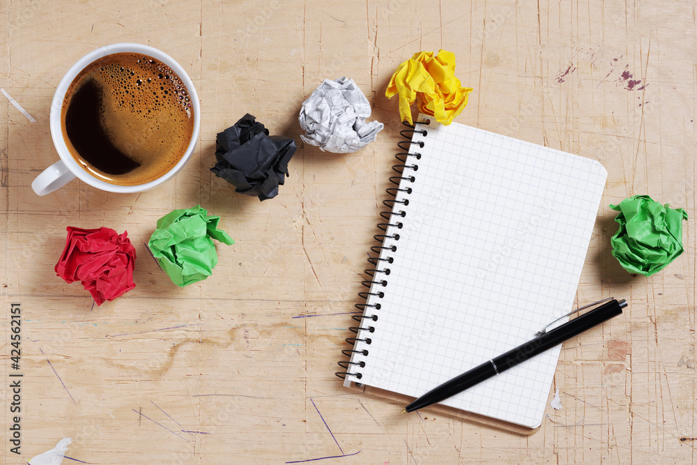 Notepad with pen, coffee and paper balls