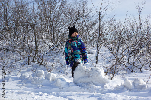 The child rolls a ball of snow. Winter fun outdoors