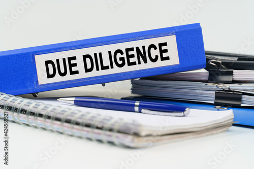 On the table are a notebook, a pen, documents and a folder with the inscription - DUE DILIGENCE