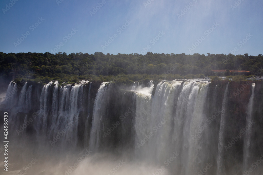 Natural world wonder. View of the Iguazu falls seen from Garganta del Diablo, in the frontier between Argentina and Brazil. The waterfalls falling white water texture and mist in the tropical forest. Natural world wonder. View of the Iguazu falls seen from Garganta del Diablo, in the frontier between Argentina and Brazil. The waterfalls falling white water texture and mist in the tropical forest.