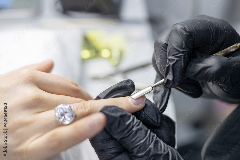 process of manicure in the salon on long nails, pushing back the cuticle with a special tool