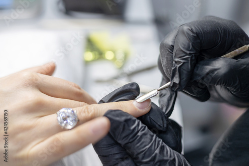 process of manicure in the salon on long nails  pushing back the cuticle with a special tool