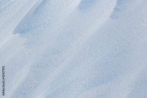 Beautiful winter background with snowy ground. Natural snow texture. Wind sculpted patterns on snow surface. © Andrei Stepanov