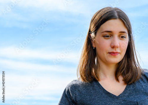 Portrait of a young woman against a blue sky with clouds