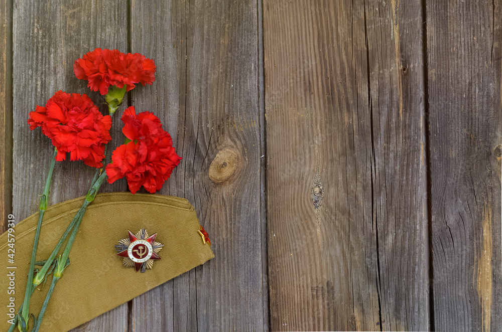 Victory Day.Order of the red star with the Russian inscription Patriotic war on a wooden background with red carnations.Celebration on may 9 Victory Day.Order of the red star with the Russian inscription Patriotic war on a wooden background with red carnations.Celebration on may 9