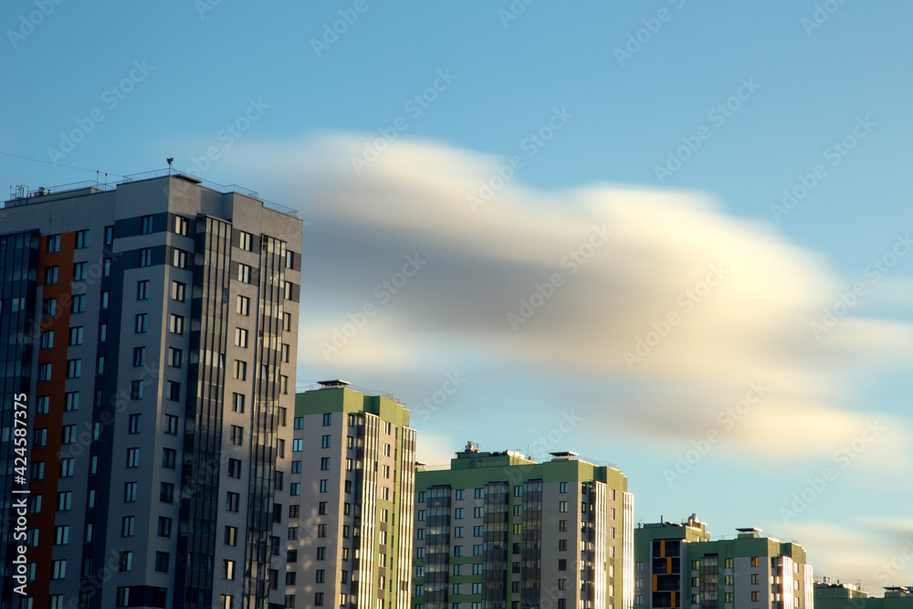 Long exposure view of blurry clouds over the blue sky over high-rise buildings.City landscape. 