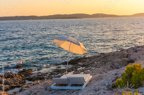Fototapeta Naklejka Na Ścianę i Meble -  Beach umbrella and loungers on the beach at sunset, island of Hvar, Croatia