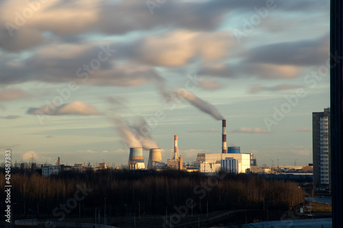 A long exposure view of the smoking chimneys of the power plant against the backdrop of a beautiful sunset sky. Southern thermal power plant in St. Petersburg. Air pollution. Ecology problems. 