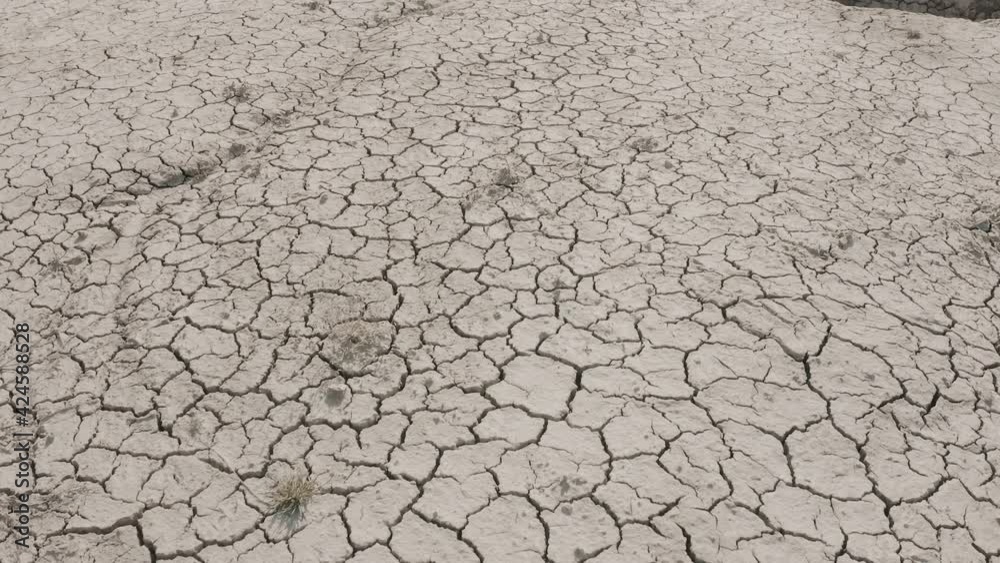 Dynamic shot of cracked soil ground of dried lake or river in mountains. Land destroyed by erosion and global warming - ecological issues concept Dynamic shot of cracked soil ground of dried lake or river in mountains. Land destroyed by erosion and global warming - ecological issues concept